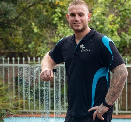 Lachy Kemp from Poolsafe Pool & Spa Inspections leaning on a pool fence.